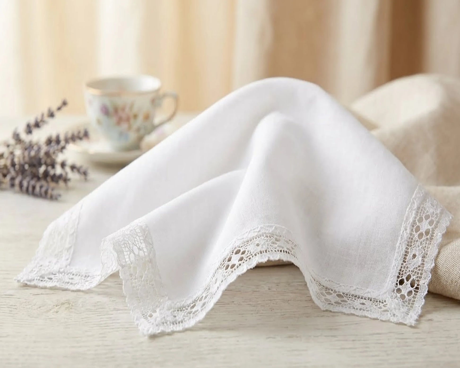White lace-trimmed handkerchief on a wooden surface with a blurred background