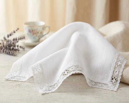 White lace-trimmed handkerchief on a wooden surface with a blurred background