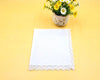White lace doily on a yellow background with a small vase of flowers.