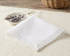 White lace-trimmed handkerchief on a light surface with a woven basket in the background.