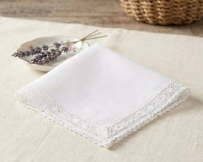 White lace-trimmed handkerchief on a light surface with a woven basket in the background.