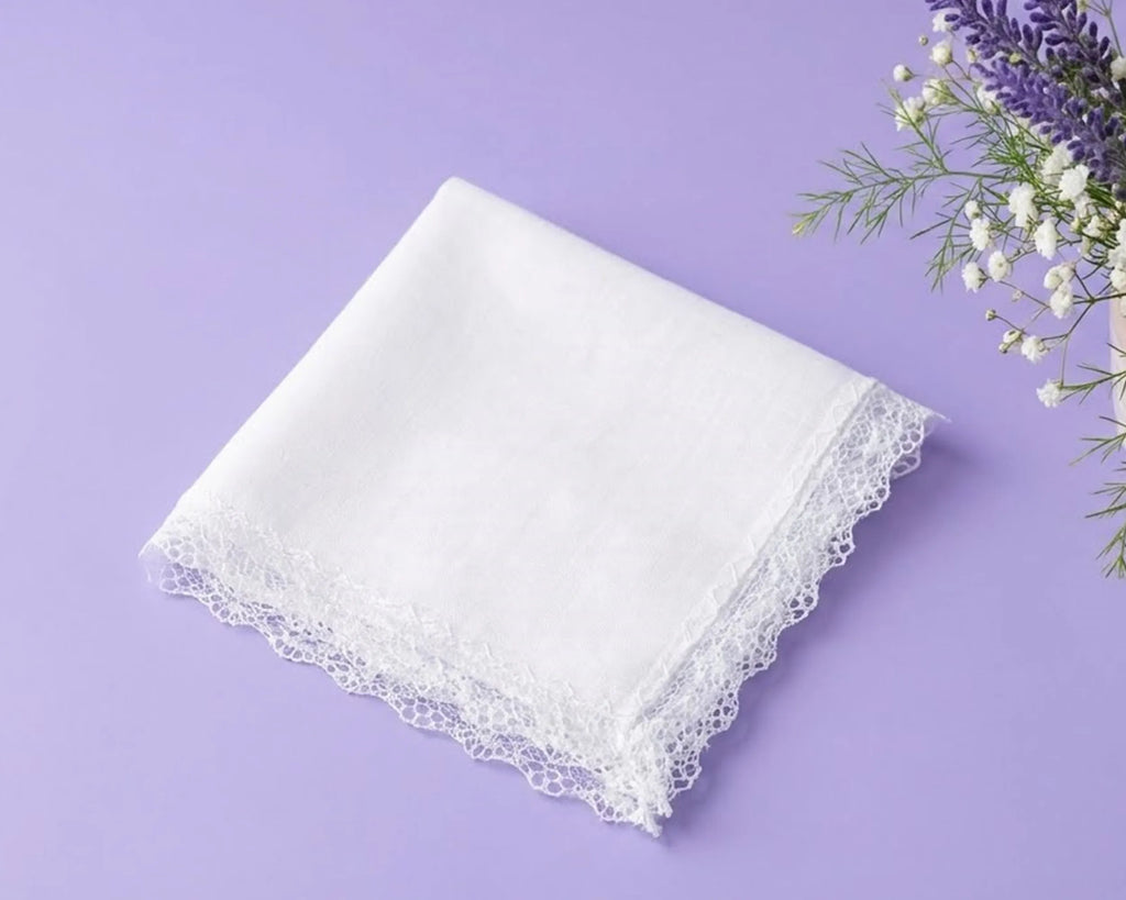 White lace-trimmed handkerchief on a purple background with flowers.