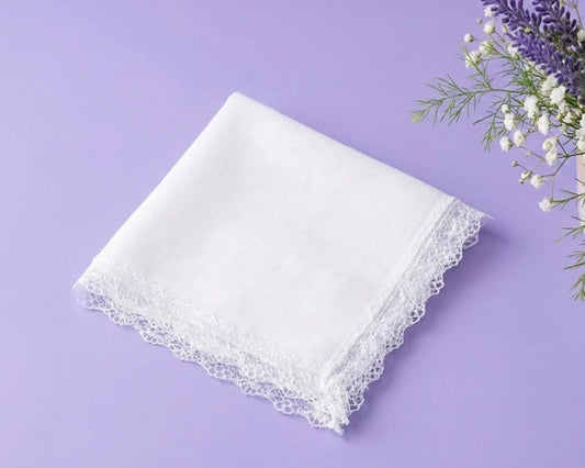 White lace-trimmed handkerchief on a purple background with flowers.