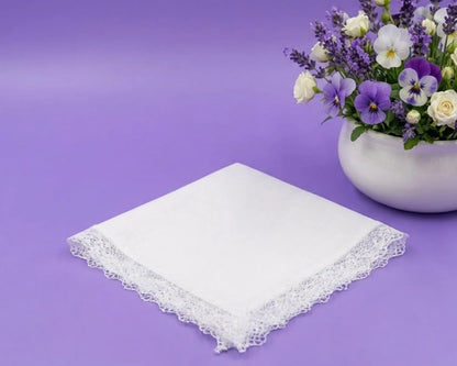 White lace handkerchief on a purple background with a vase of flowers.