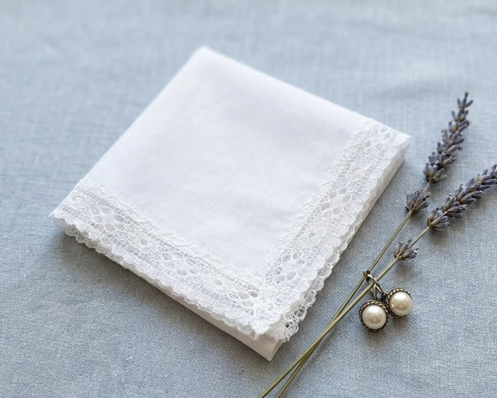 White lace handkerchief on a gray surface with lavender and earrings.
