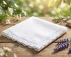 White lace handkerchief on a wooden surface with flowers in the background