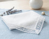 White lace handkerchief on a light blue surface with a vase and lavender in the background.