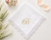 White lace handkerchief with gold letter 'B' on a light surface with decorative elements.
