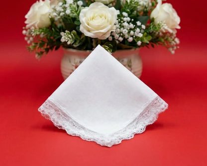White lace handkerchief on a red background with a vase of white flowers.