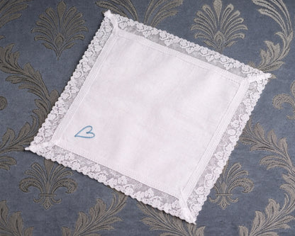 White lace hanky with a blue heart on a patterned fabric background