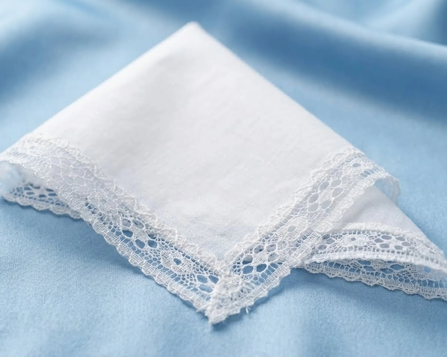 White lace-trimmed handkerchief on a light blue fabric background