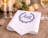 White napkin with 'A&R' monogram on a wooden table with candles and flowers.