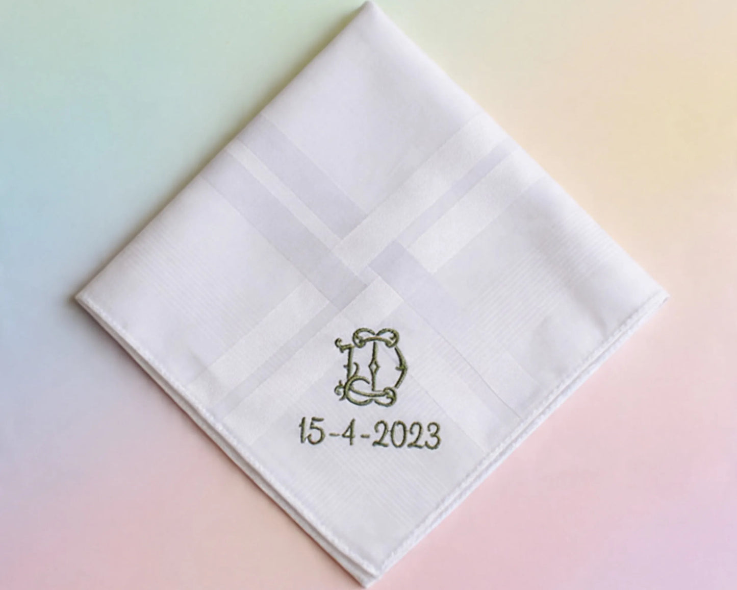 White quilted handkerchief with monogram 'D' and date '15-4-2023' on a pastel gradient background