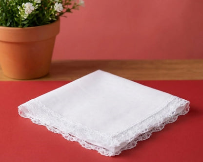 White lace handkerchief on a red surface with a potted plant in the background