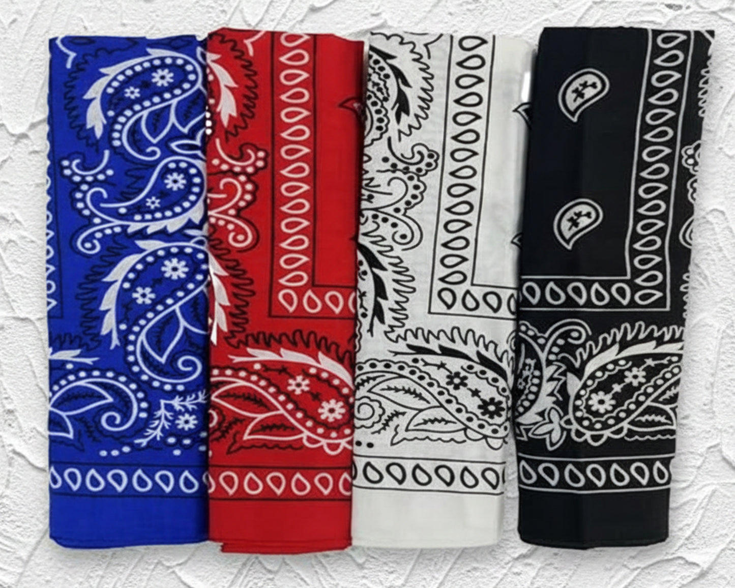 Stack of folded black cotton bandanas with white paisley prints Four rolled cotton bandanas