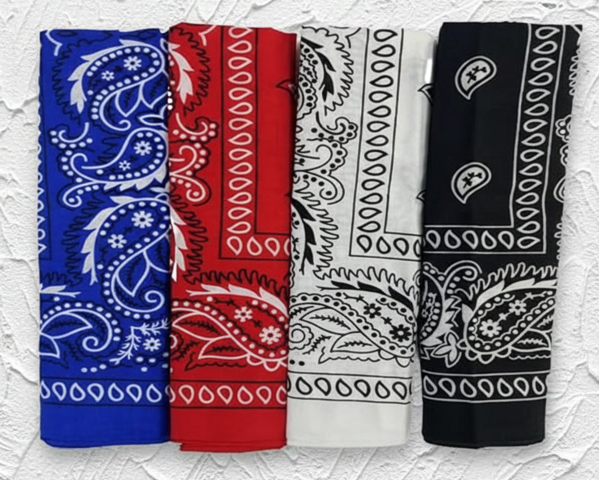Stack of folded black cotton bandanas with white paisley prints Four rolled cotton bandanas