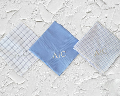 Close up of blue solid and grid patterned cotton handkerchiefs with bold black CSL monogram embroidery.