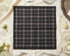 Black and white plaid fabric on a light surface with flowers and ribbons.