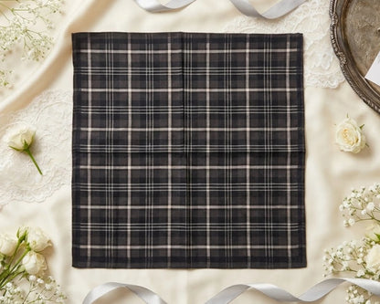 Black and white plaid fabric on a light surface with flowers and ribbons.