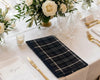 Elegant table setting with plaid napkin, glasses, and flowers.
