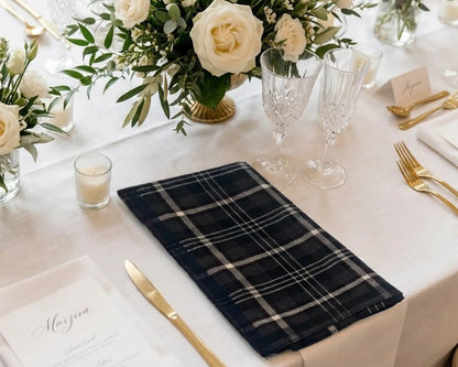 Elegant table setting with plaid napkin, glasses, and flowers.