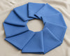 Blue fabric folded into a circular wreath on a beige background