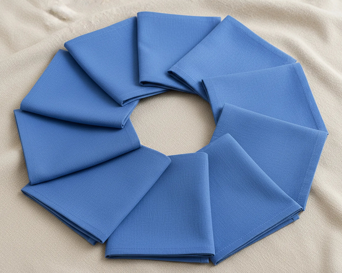Blue fabric folded into a circular wreath on a beige background