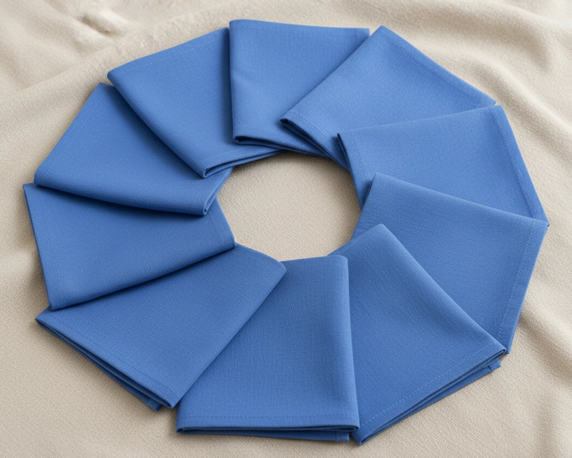 Blue fabric folded into a circular wreath on a beige background