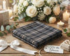 Plaid hanky on a wooden table with flowers, candles, and a tag for the groom.