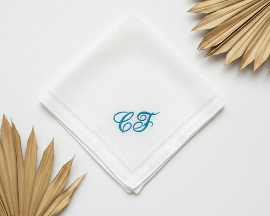 A white linen hemstitch handkerchief featuring custom blue cursive CF monogrammed initials.