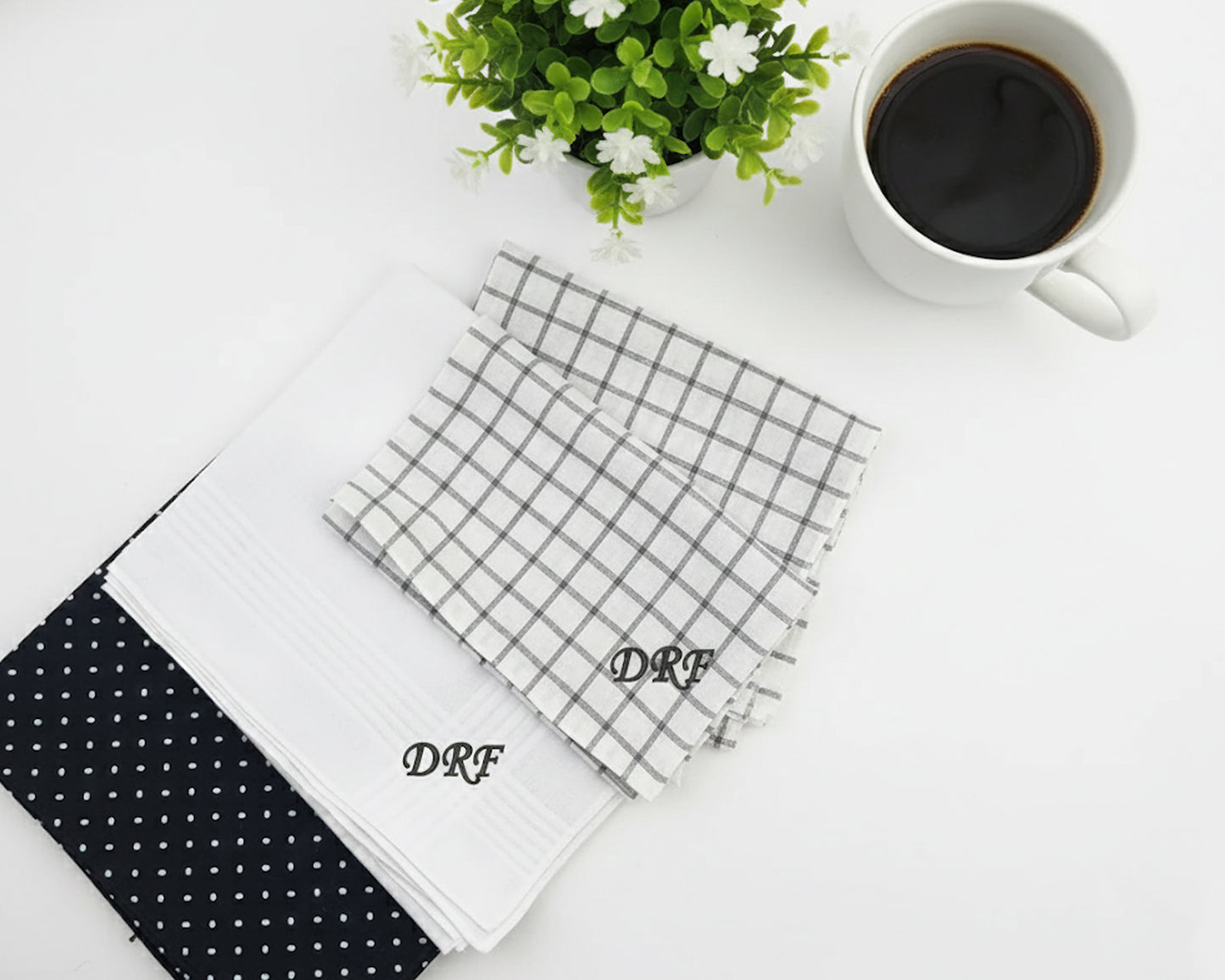 Three custom cotton handkerchiefs in navy plaid white diamond and solid blue patterns with red diamond monogrammed initials.