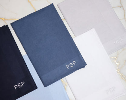 Three personalized cotton handkerchiefs in navy and sky blue featuring custom gold diamond CPM monogram embroidery.