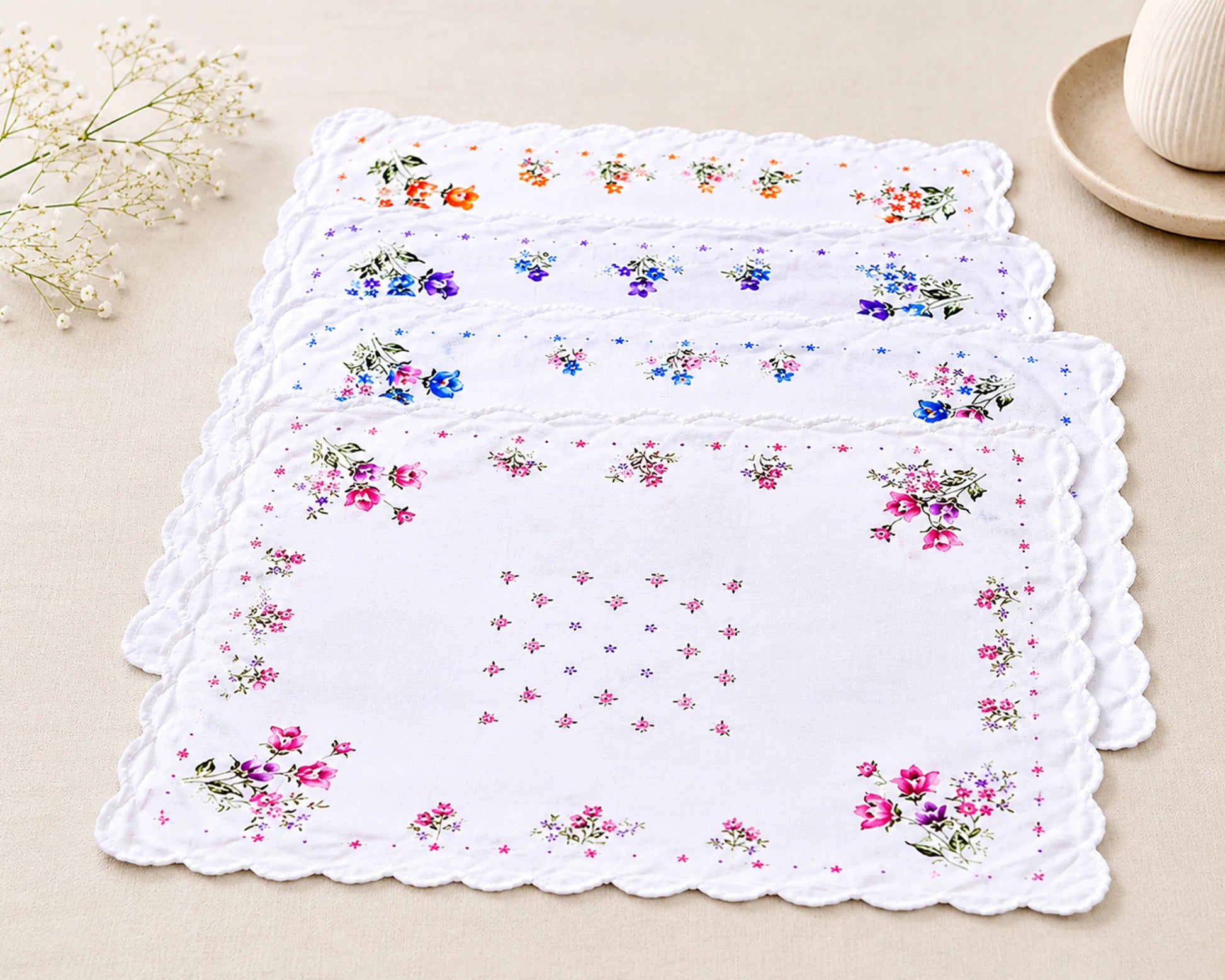 Set of floral placemats on a beige surface with a decorative edge.