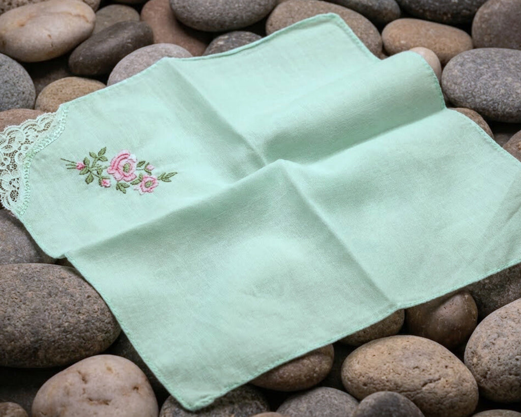 Two green embroidered handkerchiefs on a bed of stones
