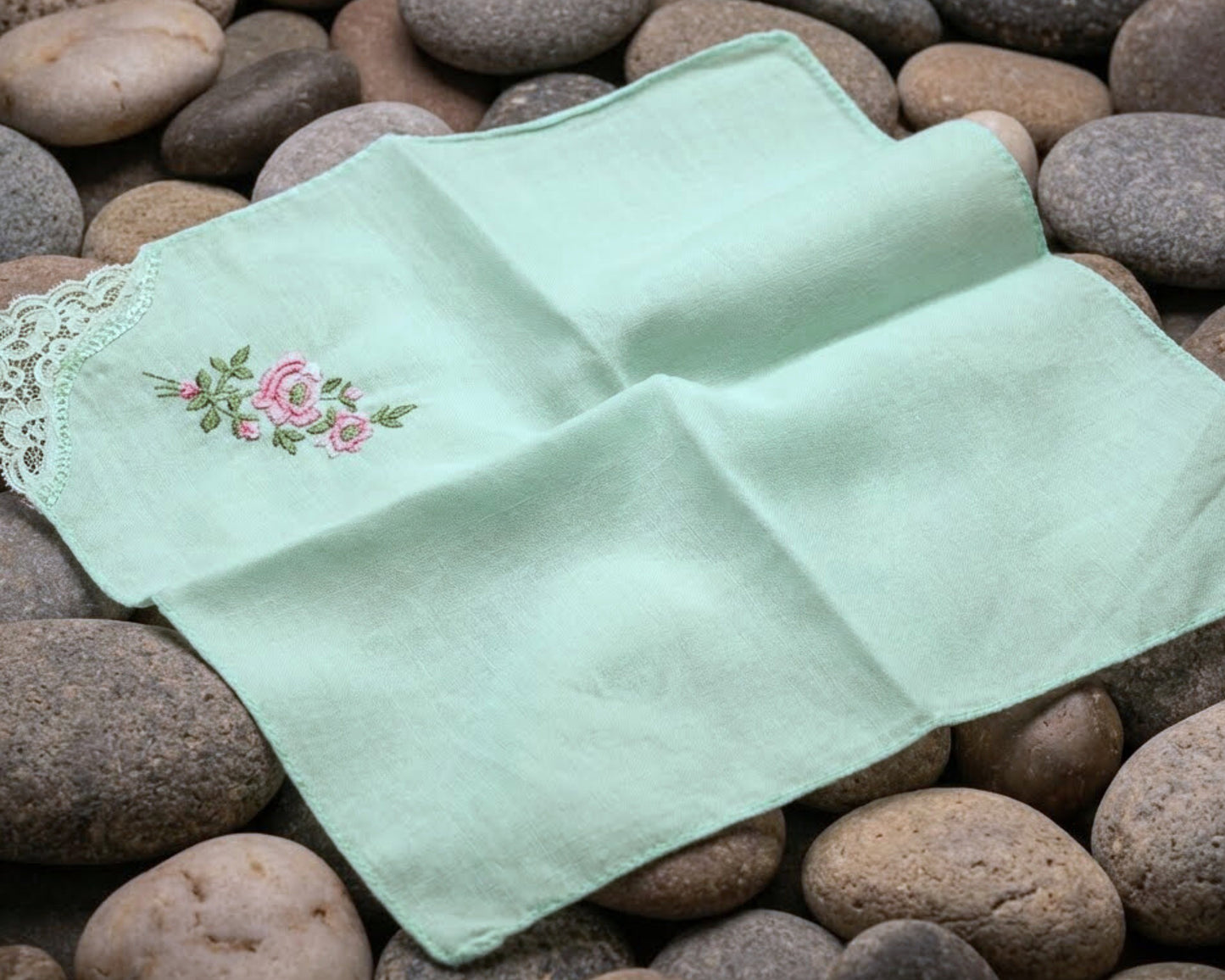 Two green embroidered handkerchiefs on a bed of stones