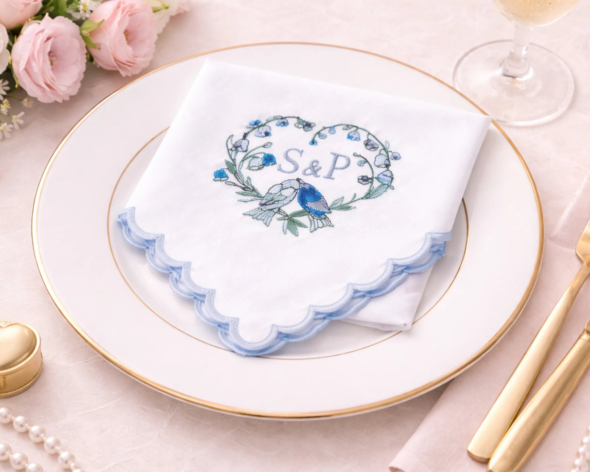 hanky with 'S&P' design on a plate with floral decorations and gold cutlery.