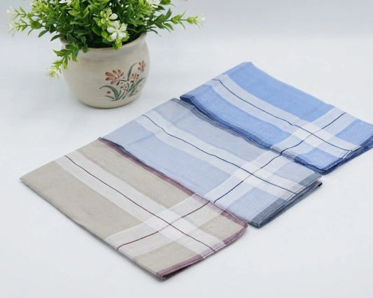 three folded plaid cloths on a white surface with a potted plant in the background.