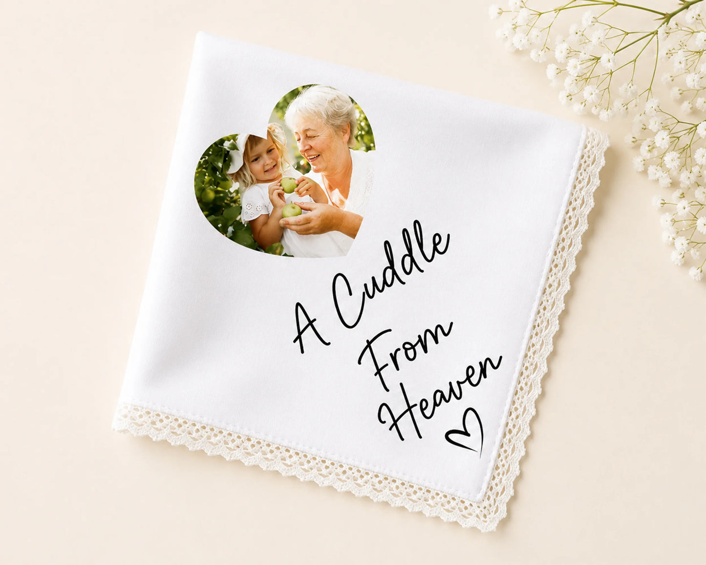 White handkerchief with photo of an elderly woman and a child, and text 'A Cuddle From Heaven' on a beige background.