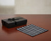 Black gift box with a bow and checkered cloth on a wooden surface