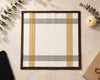 Framed artwork with geometric design on a textured surface with leaves and a flower.
