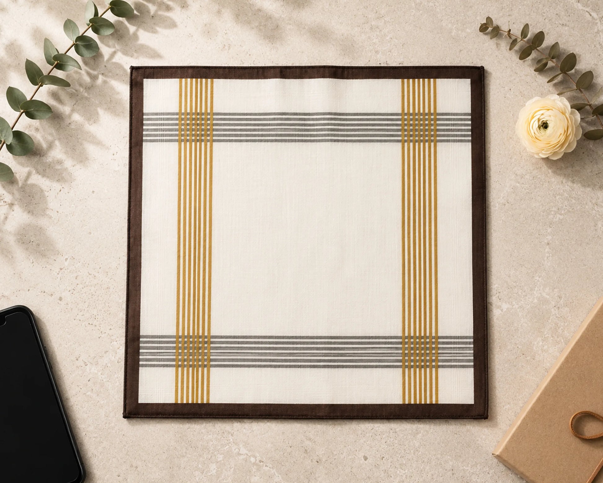 Framed artwork with geometric design on a textured surface with leaves and a flower.