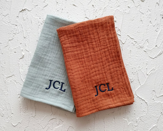 Three custom muslin gauze handkerchiefs in beige rust and sage colors featuring white and navy monograms.