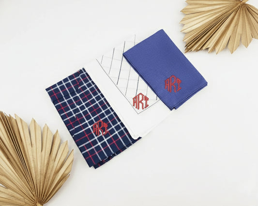 White cotton pocket square with a striped border and grey grid pattern featuring custom black script monogram embroidery.