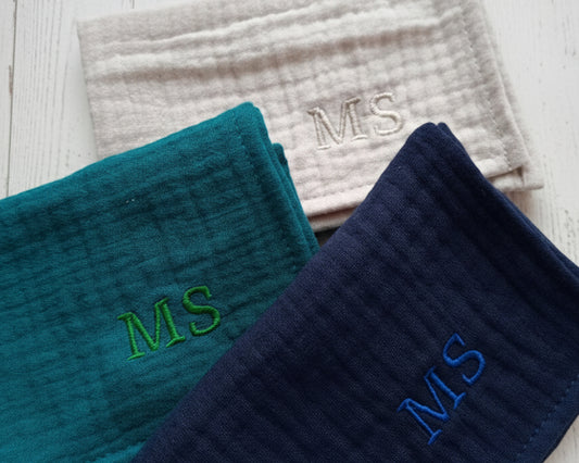 Three layered muslin handkerchiefs in teal navy blue and light grey featuring custom MS initial embroidery.
