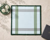 Plaid placemat on a marble surface with a black book and white flowers.