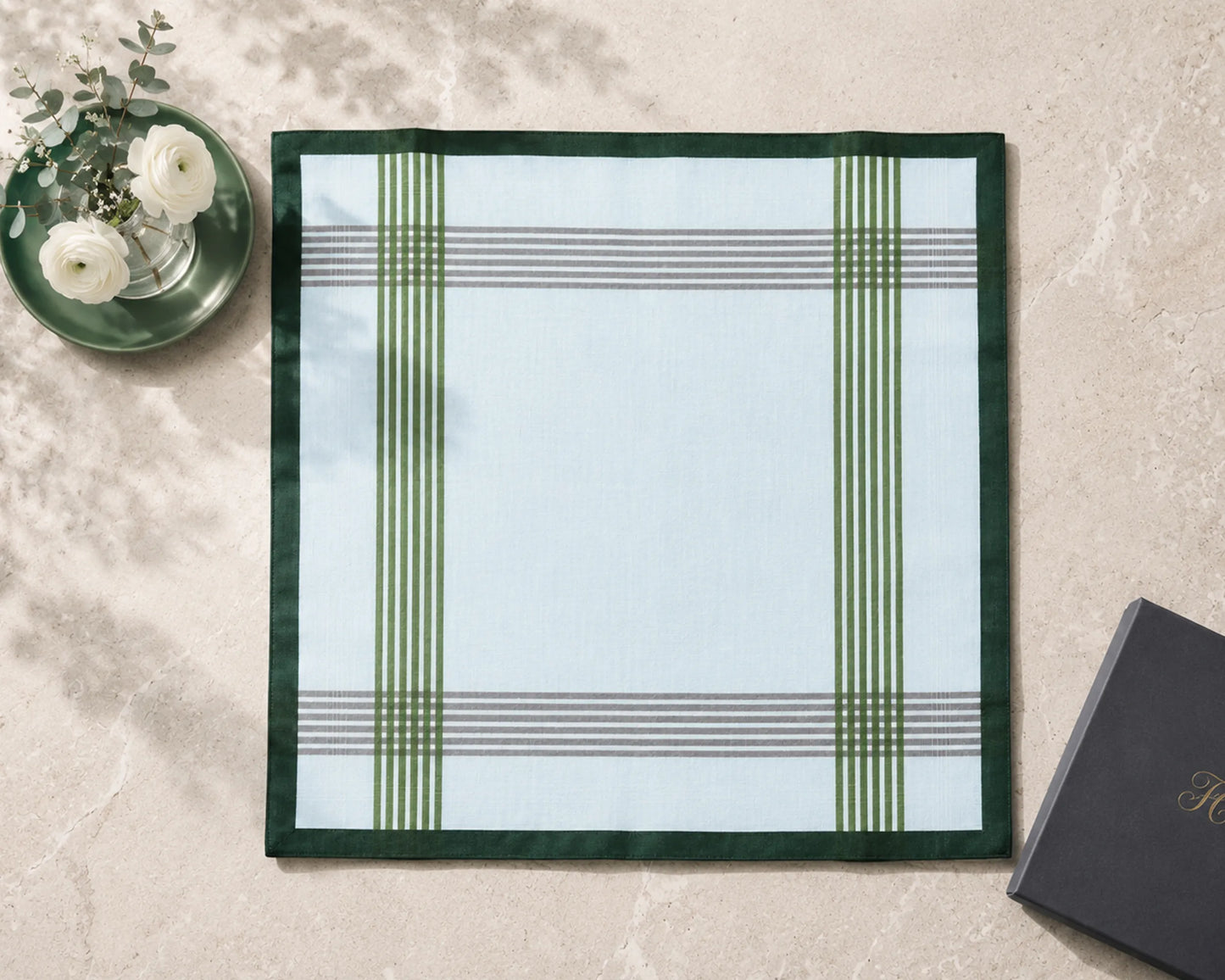 Plaid placemat on a marble surface with a black book and white flowers.