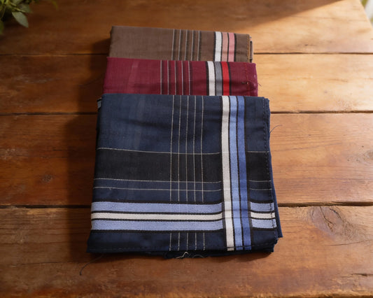 Two folded fabric swatches on a wooden surface, one brown and red striped, the other blue with white stripes.