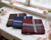 Folded fabric hanky on a white surface with flowers in the background
