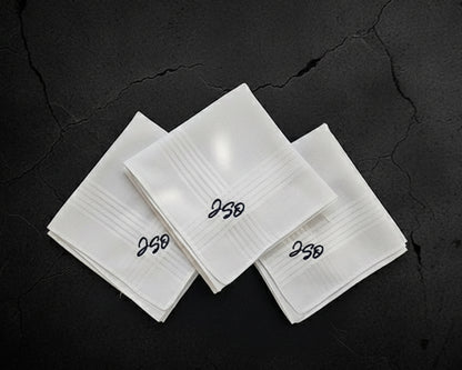 Three white folded cotton handkerchiefs with custom black script monograms 