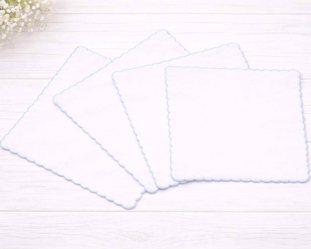 Three white rectangular placemats on a light wooden surface with a blurred floral background.